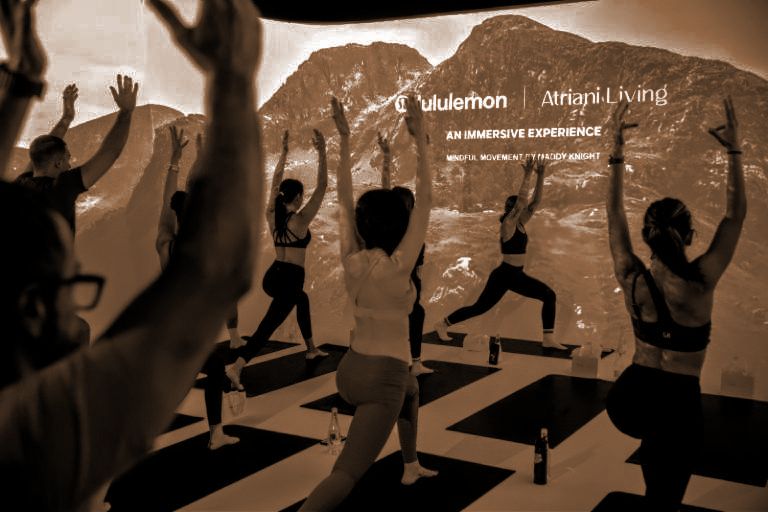 Yoga class in warrior pose inside a room fully projection-mapped with mountain landscape for Lululemon immersive experience